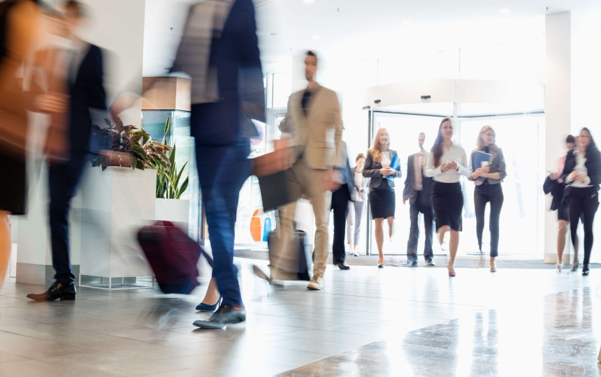 a lobby with blurred business men and women walking in