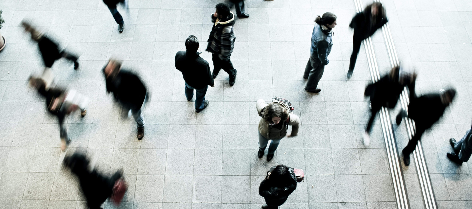 aerial view of blurred people walking different directions on a platform