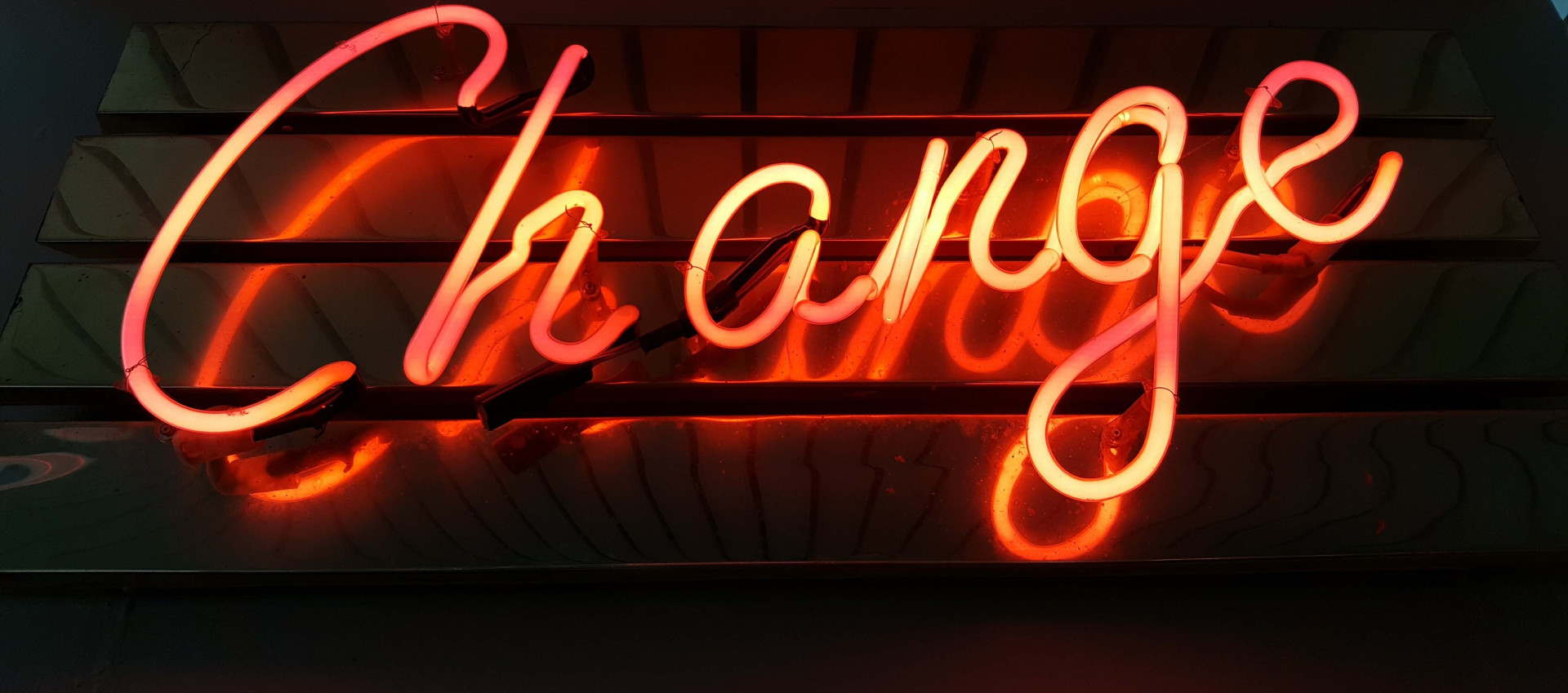 the word "change" lit up in red neon colour on a dark background