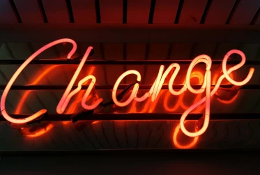 the word "change" lit up in red neon colour on a dark background