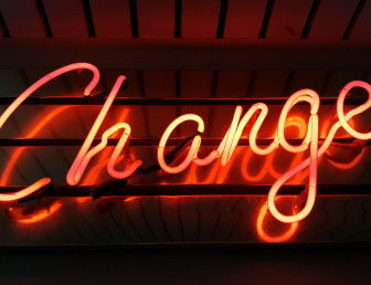 the word "change" lit up in red neon colour on a dark background