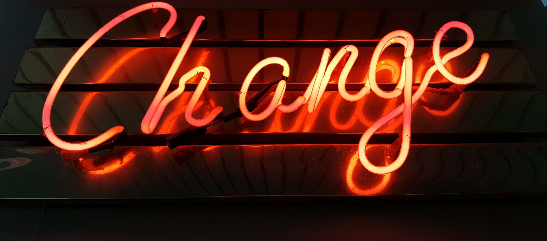 the word "change" lit up in red neon colour on a dark background