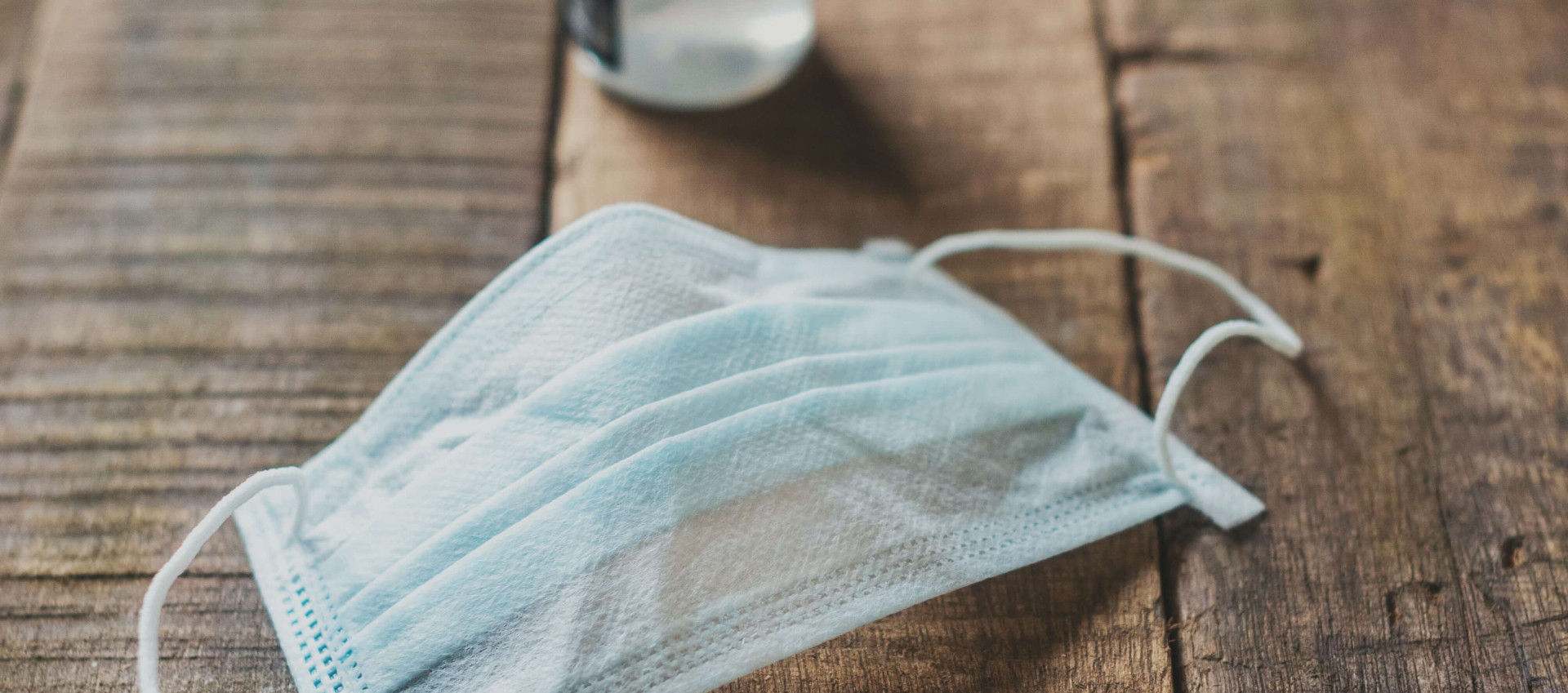 wooden table with blue surgical face mask and sanitiser