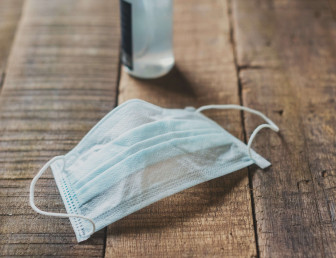 wooden table with blue surgical face mask and sanitiser