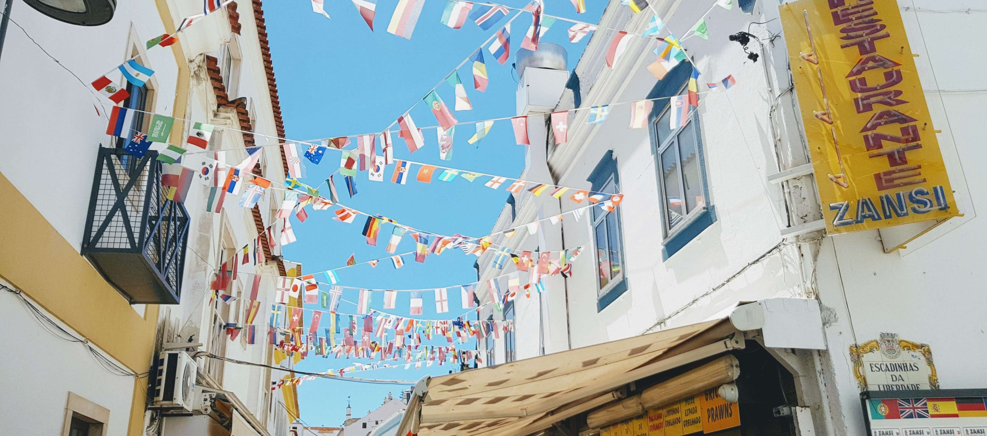 low angle view of bunting of several international flags attached to opposite buildings