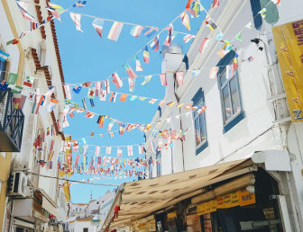 low angle view of bunting of several international flags attached to opposite buildings