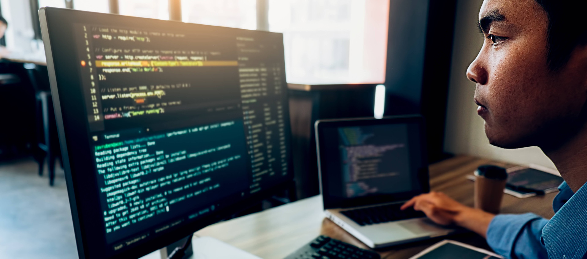 side view of man working on coding with one hand on keyboard and the other on the laptop