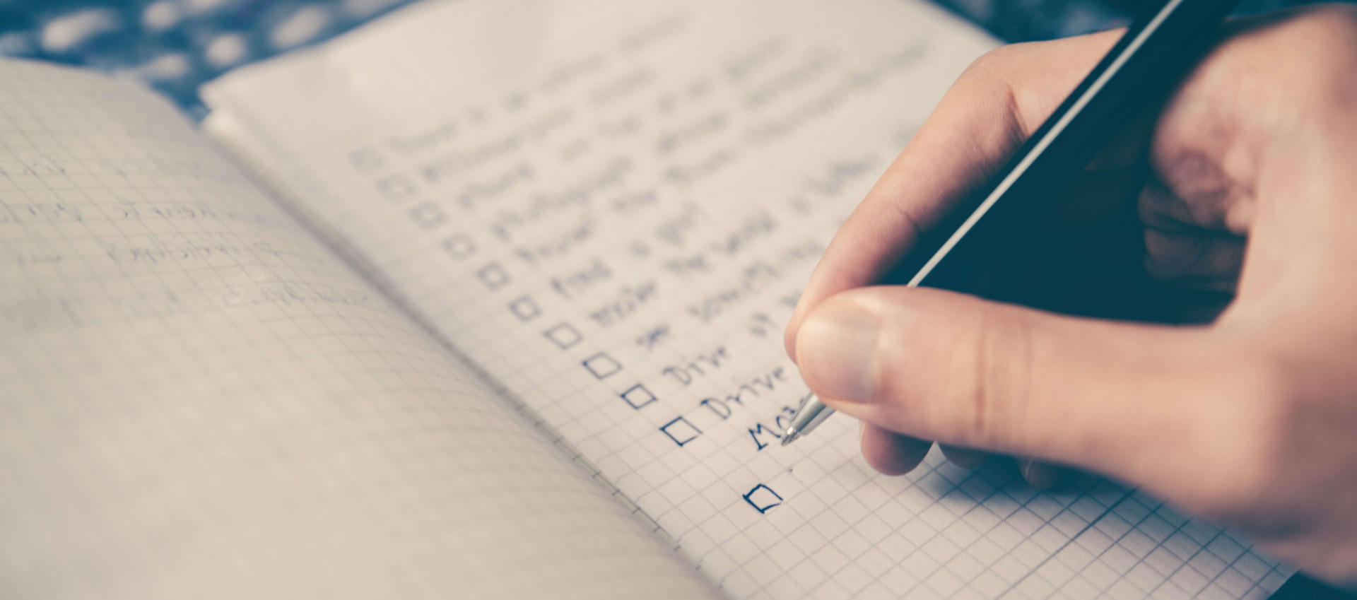 persons hand holding pen writing in a notebook