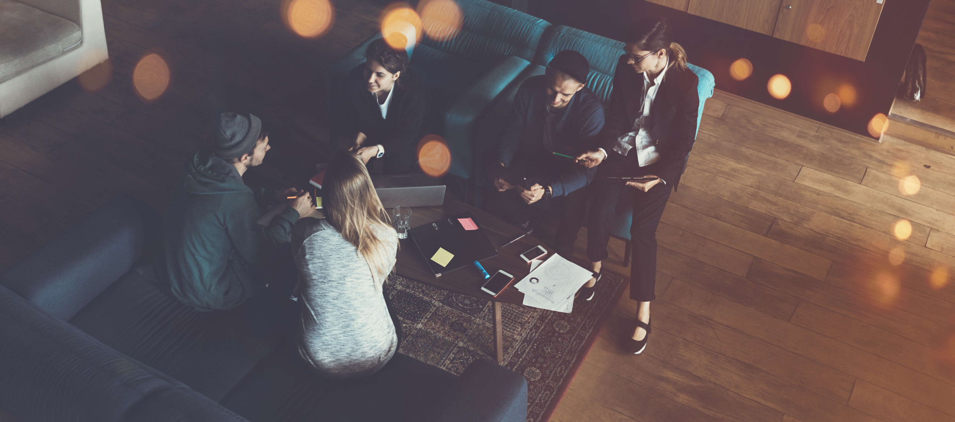 birds eye view of five people sitting in an lobby with laptop and office materials on the table