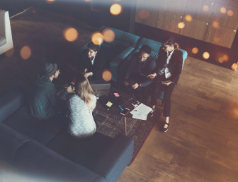 birds eye view of five people sitting in an lobby with laptop and office materials on the table