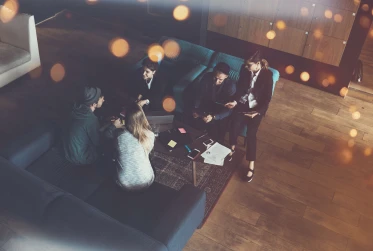birds eye view of five people sitting in an lobby with laptop and office materials on the table