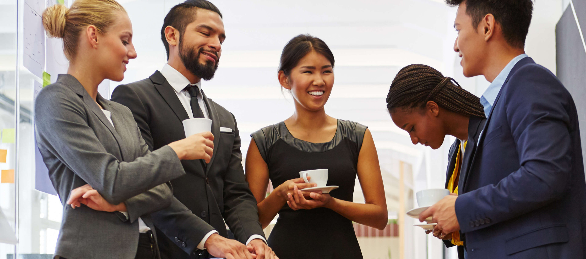 five people in smart clothing talking in office hallway