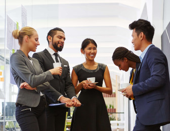 five people in smart clothing talking in office hallway