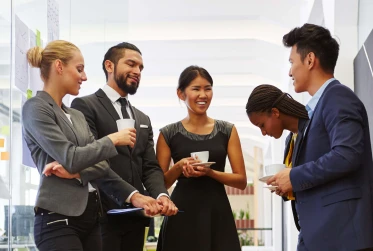 five people in smart clothing talking in office hallway
