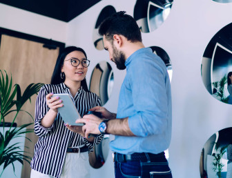 low angle view of two people interacting while they both hold tablet device