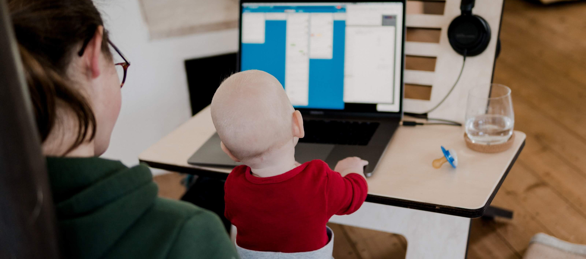 woman in casual clothing working from home with baby on her knees