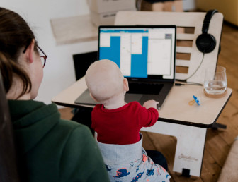 woman in casual clothing working from home with baby on her knees