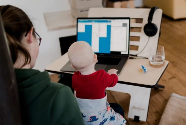 woman in casual clothing working from home with baby on her knees