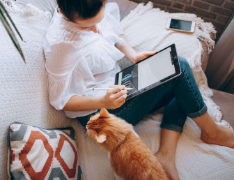 woman in casual clothing sitting on the sofa with cat and working from home