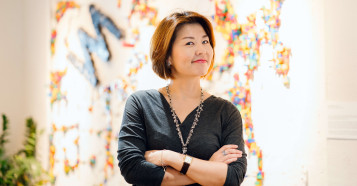eye level view of woman grinning with arms folded looking at the camera with multicoloured background