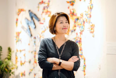 eye level view of woman grinning with arms folded looking at the camera with multicoloured background 