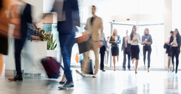 a lobby with blurred business men and women walking in