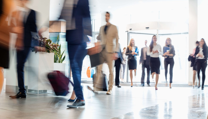 a lobby with blurred business men and women walking in