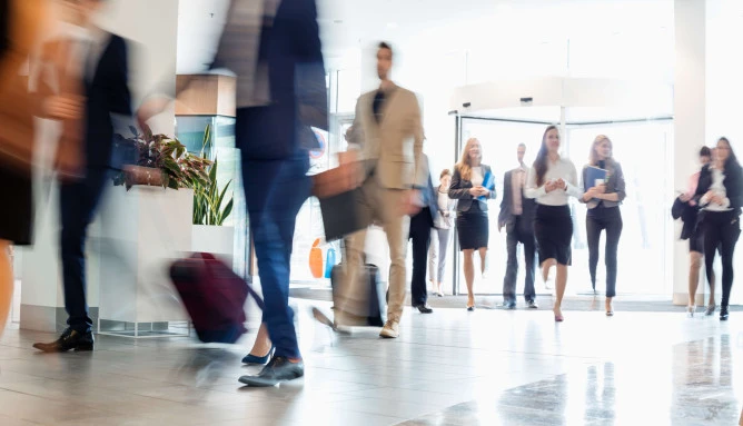 a lobby with blurred business men and women walking in