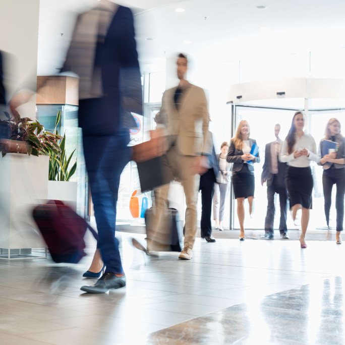 a lobby with blurred business men and women walking in
