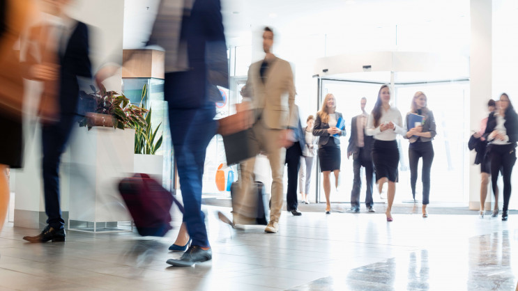 a lobby with blurred business men and women walking in