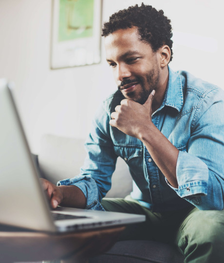 man wearing casual clothes sitting on sofa looking at laptop