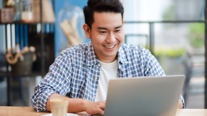 man smiling in casual wear on a laptop in an office