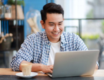 man smiling in casual wear on a laptop in an office