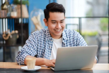 man smiling in casual wear on a laptop in an office
