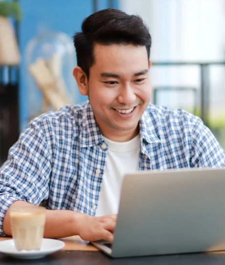 man smiling in casual wear on a laptop in an office