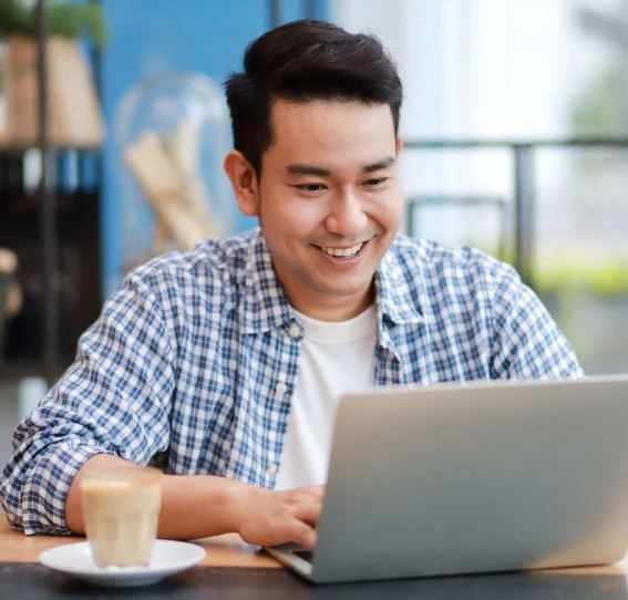 man smiling in casual wear on a laptop in an office
