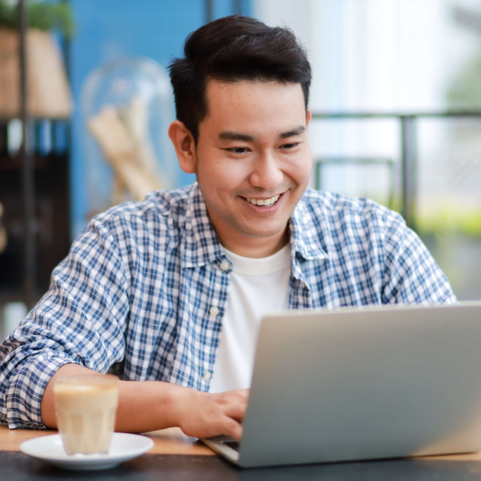 man smiling in casual wear on a laptop in an office