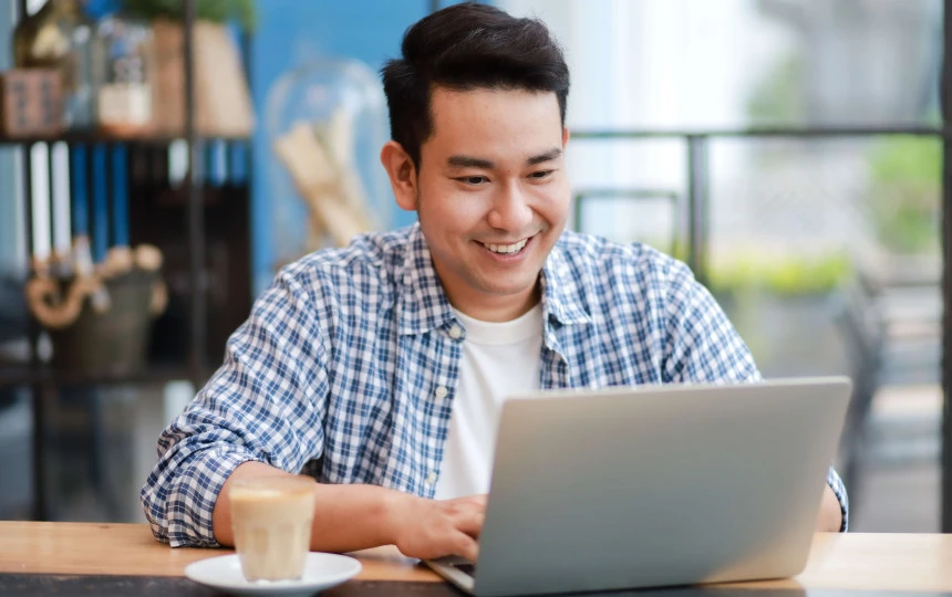 man smiling in casual wear on a laptop in an office