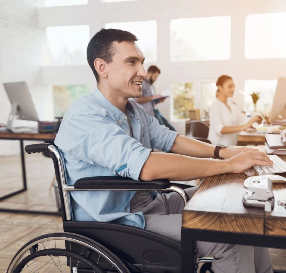 man smiling sitting in wheelchair working in office