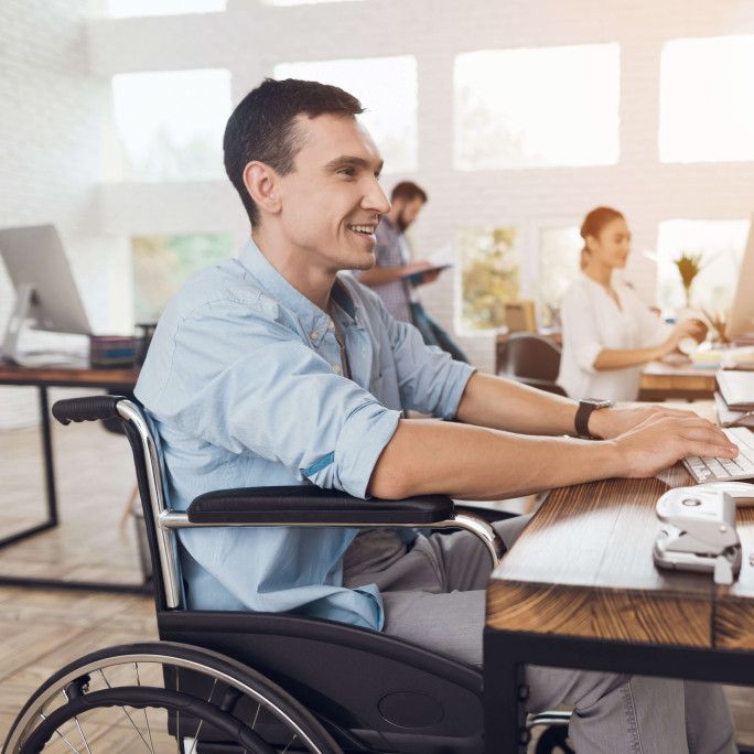 man smiling sitting in wheelchair working in office