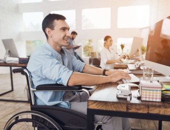man smiling sitting in wheelchair working in office