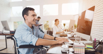man smiling sitting in wheelchair working in office