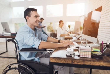 man smiling sitting in wheelchair working in office