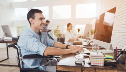 man smiling sitting in wheelchair working in office