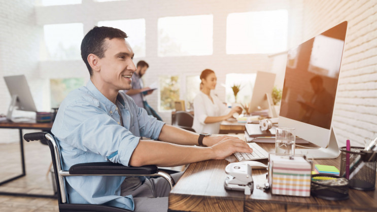 man smiling sitting in wheelchair working in office