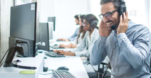 man in a suit with a headset laughing while taking call in call center