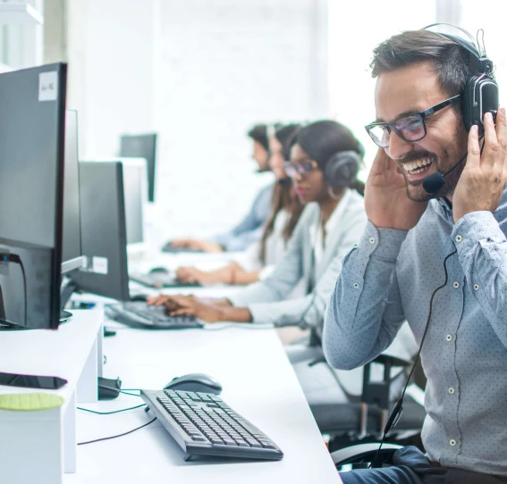 man in a suit with a headset laughing while taking call in call center