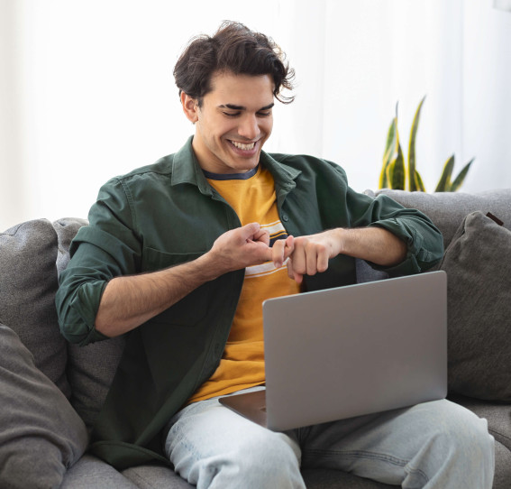 man on sofa smiling doing sign language on laptop