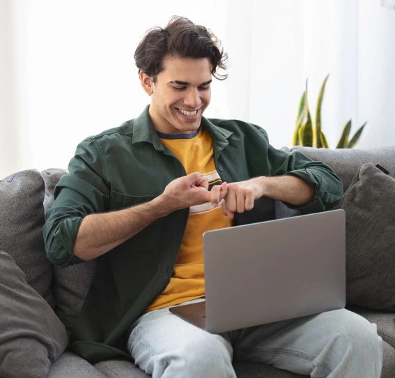 man on sofa smiling doing sign language on laptop