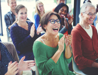group of people sitting down in causal clothing applauding while laughing and smiling